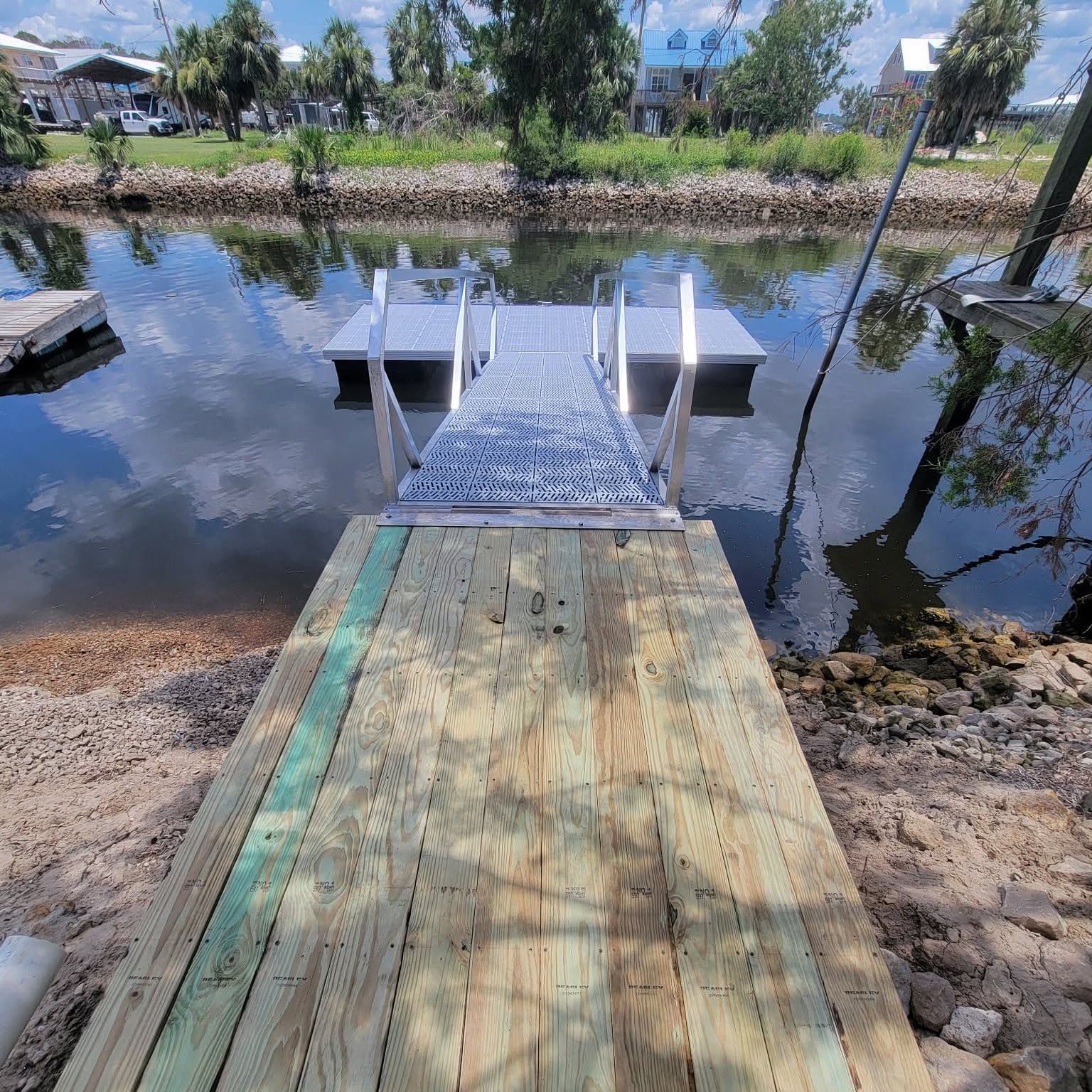 New wood walkway leading to an aluminum gangway and floating dock on calm water