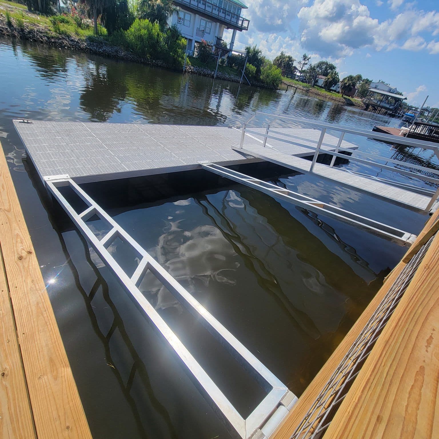 Floating dock with an open boat slip framed in aluminum, beside a new wood deck