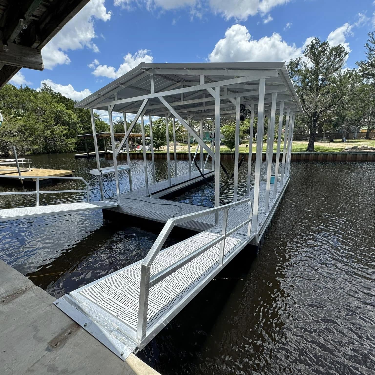 Covered boat slip with a white aluminum roof on a floating dock, reached by an aluminum walkway with handrails