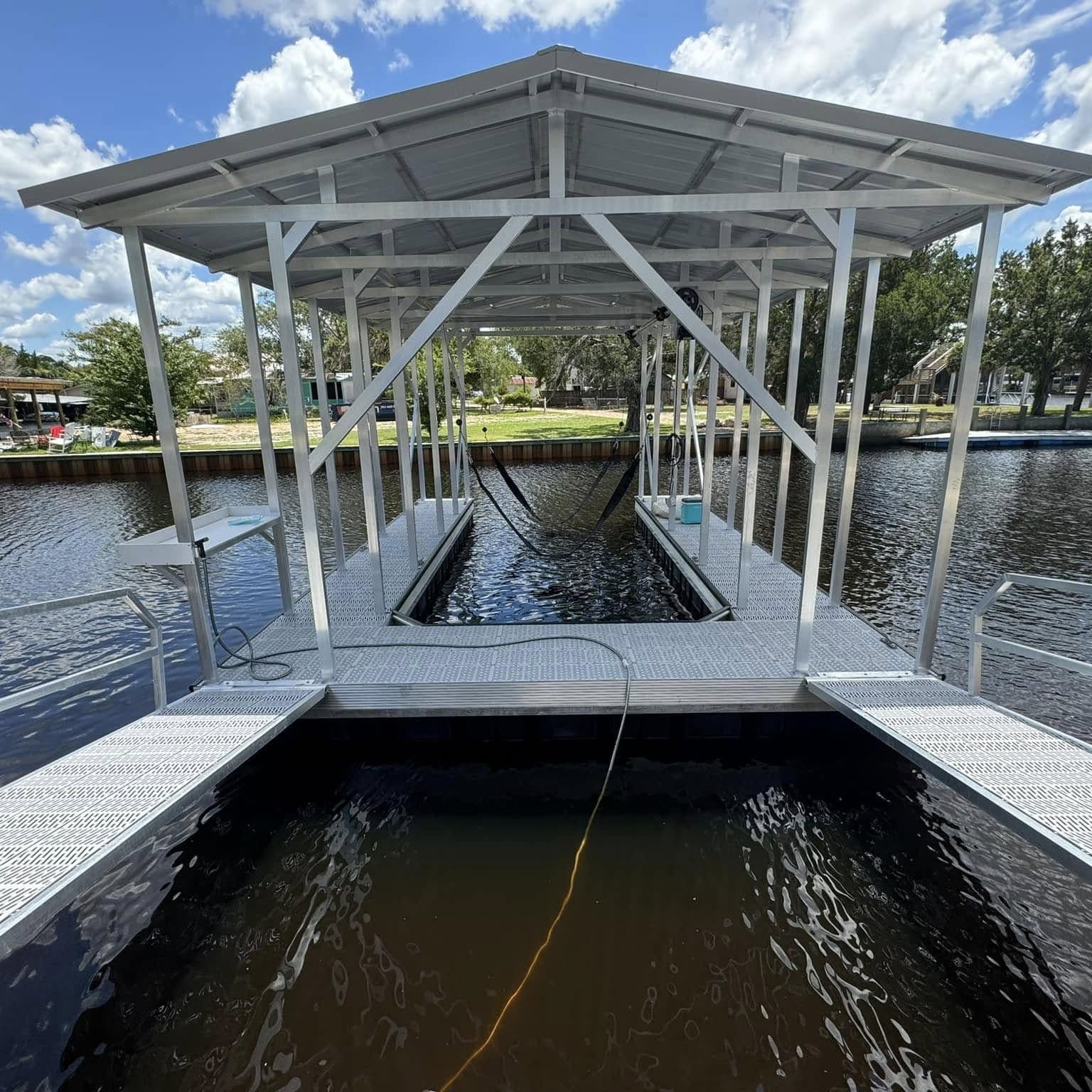 Front view of a covered floating boat slip with aluminum roof framing and grated walkways on both sides
