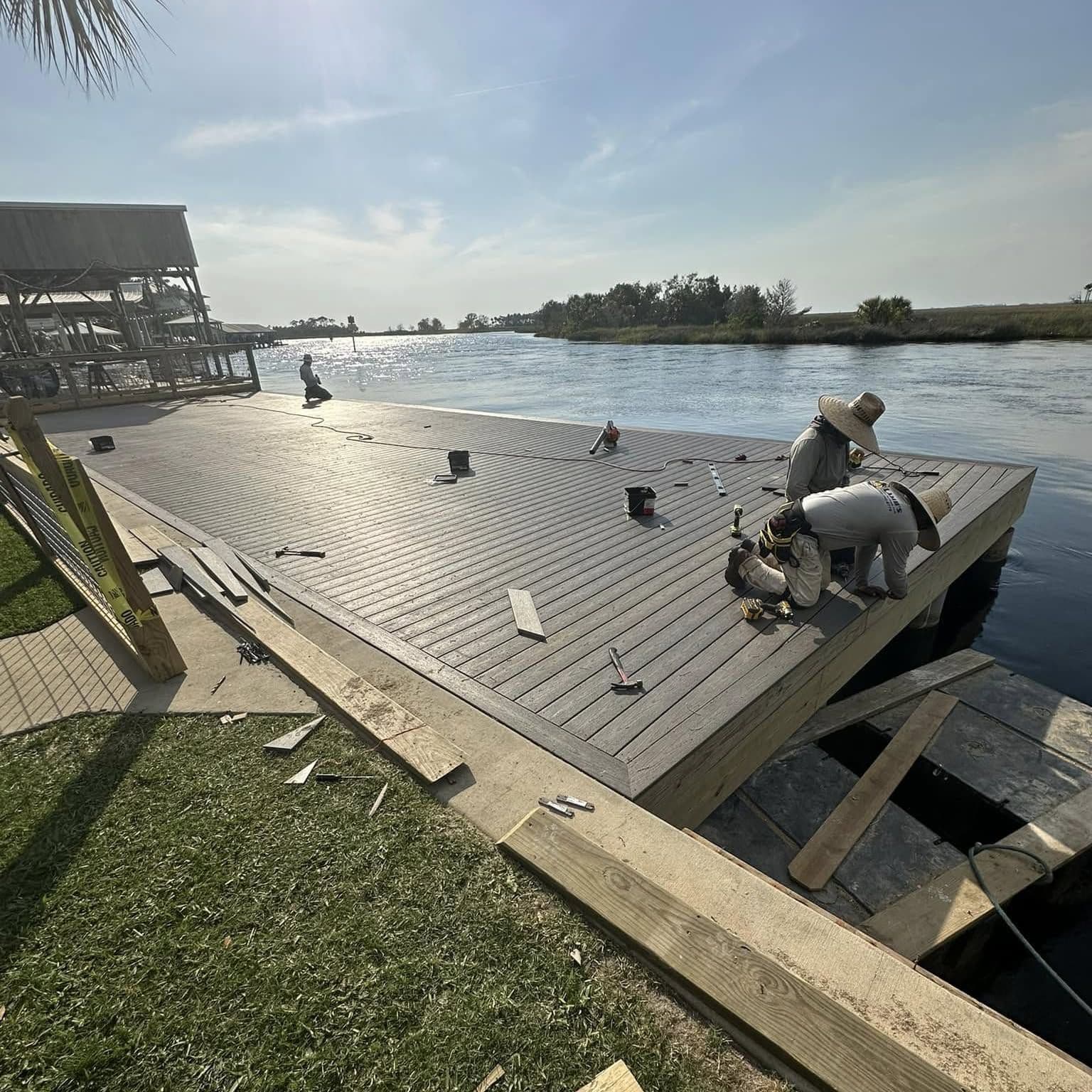 Crew member fastening gray decking boards on a new waterfront deck