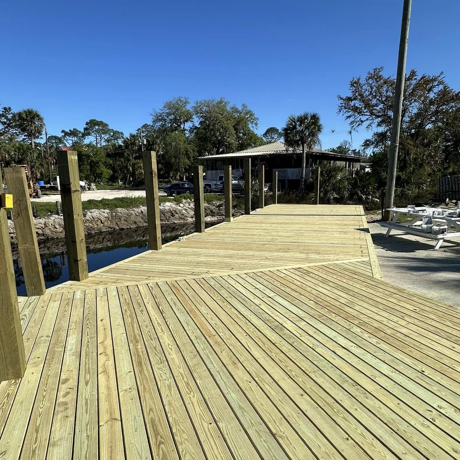 Newly built wood dock and walkway on pilings along a waterfront under a blue sky