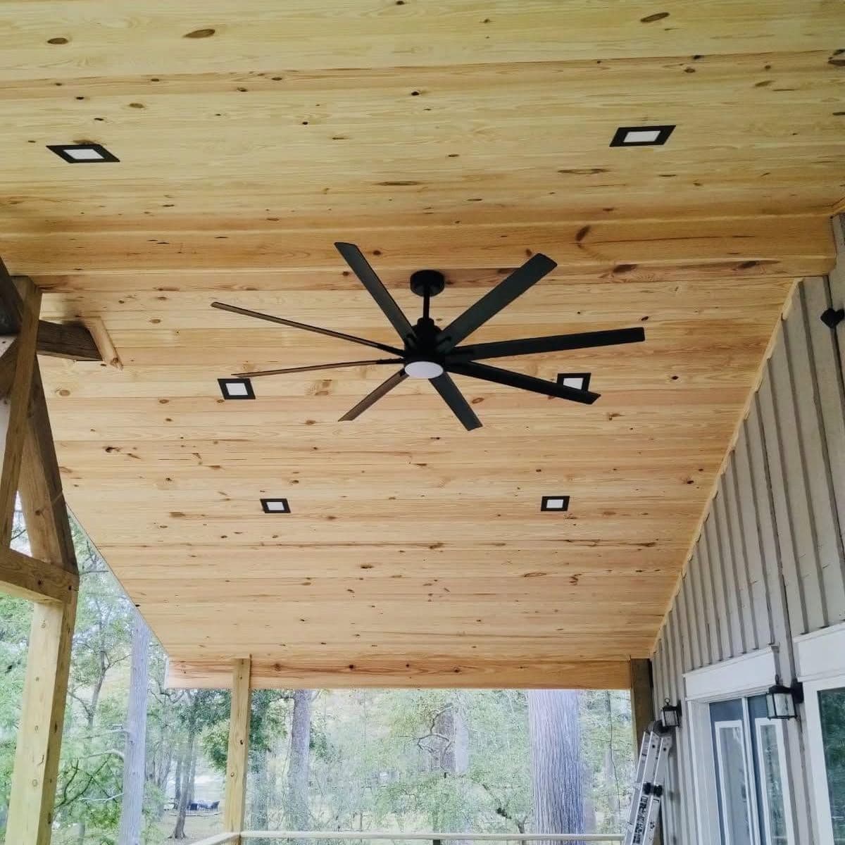 Tongue-and-groove porch ceiling with recessed lights and a black ceiling fan